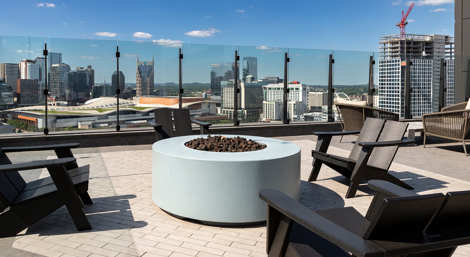 chairs and firepit on a rooftop with buildings in the background